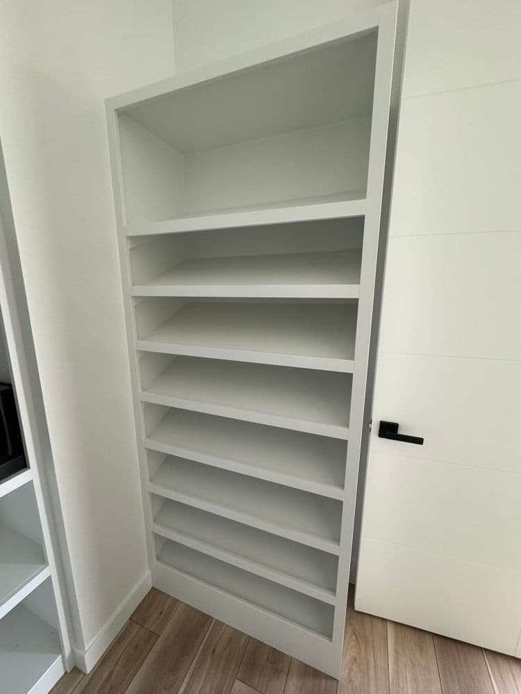 Minimalist white bookshelf with eight shelves in a modern room setting. Ideal for storage.