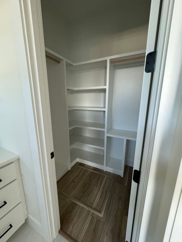 Empty closet with built-in shelves and a wooden floor, showcasing organized storage space.