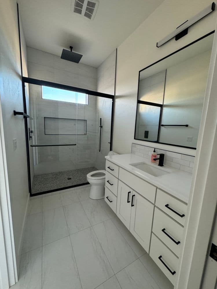 Modern bathroom with glass shower, sleek vanity, and stylish fixtures in neutral tones.