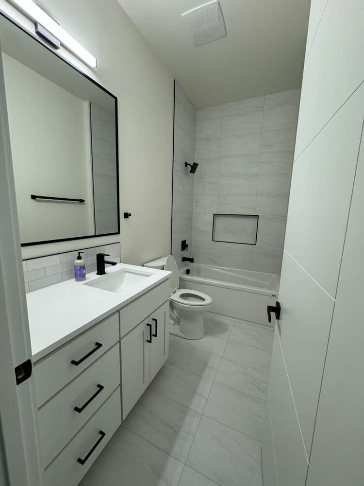 Modern bathroom featuring a sleek design, white tile, and black fixtures.