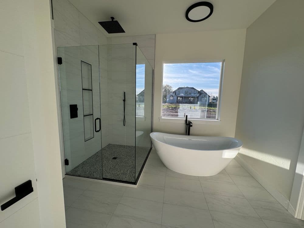 Modern bathroom featuring a glass shower, freestanding bathtub, and natural light.