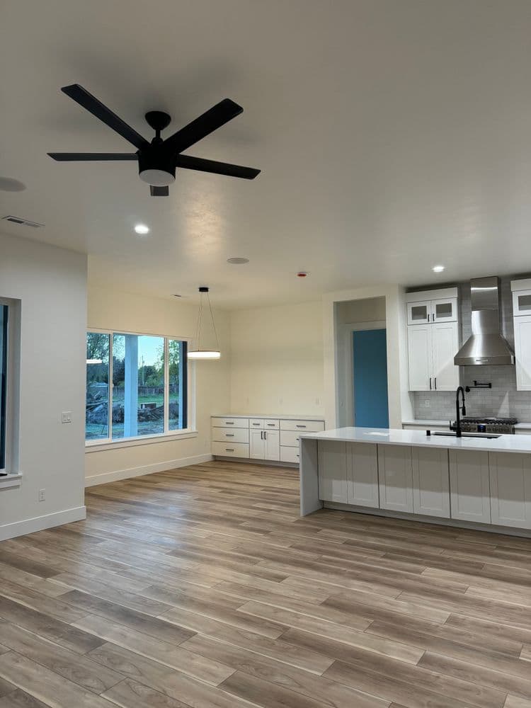 Spacious modern living room with wood floors, large windows, and ceiling fan.