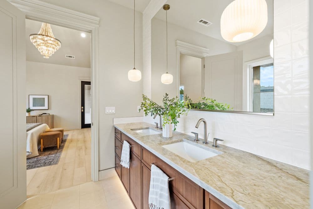 Elegant bathroom with double sinks, modern fixtures, and natural light from nearby window.