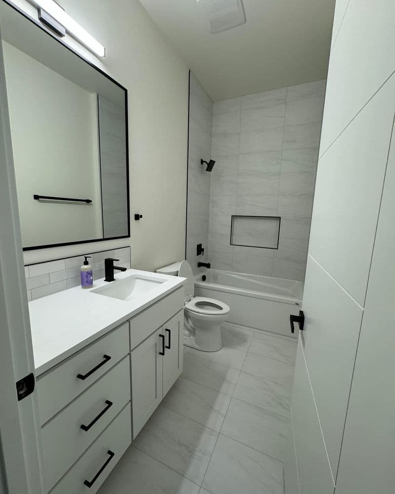 Modern bathroom design featuring a bathtub, white cabinetry, and sleek fixtures.