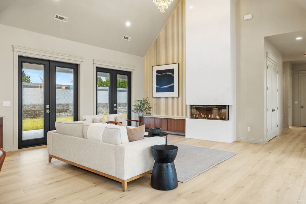 Modern living room with a fireplace, large windows, and stylish furniture.