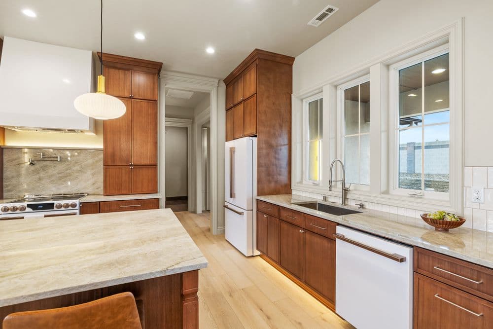 Modern kitchen with wood cabinets, marble countertops, and stainless steel appliances.