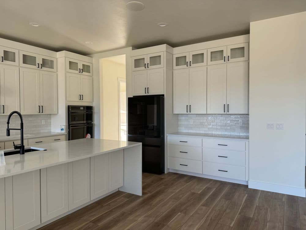 Modern kitchen with white cabinets, black appliances, and a spacious island.