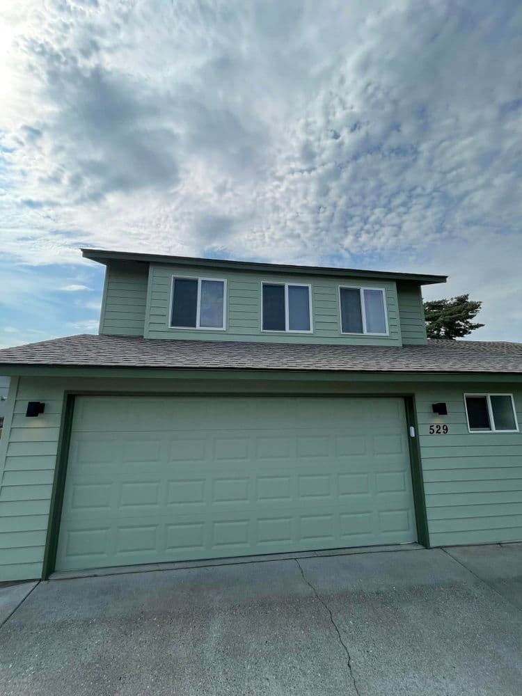 Two-story green house with three windows and a garage at 529. Clear sky in the background.
