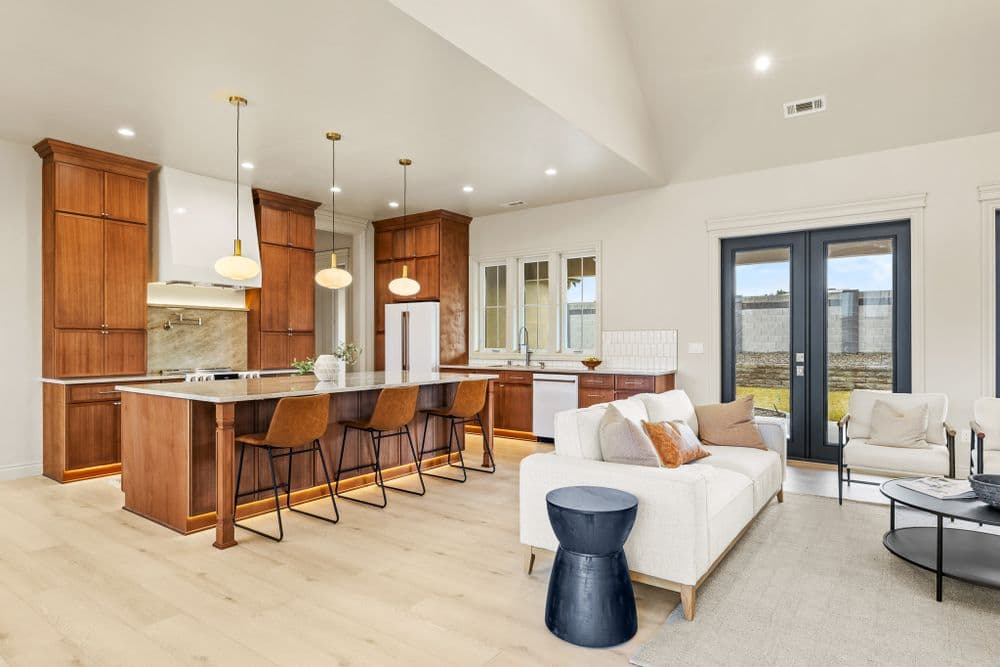 Modern kitchen with wooden cabinetry, bar seating, and bright open space near a cozy living area.