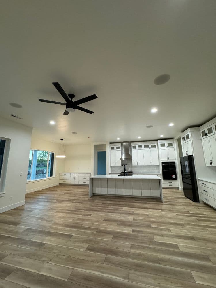 Modern kitchen with white cabinets, sleek appliances, and open layout featuring wood-like flooring.