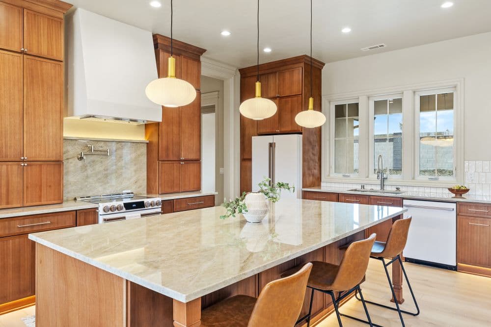 Modern kitchen with wooden cabinetry, large island, and stylish pendant lights.