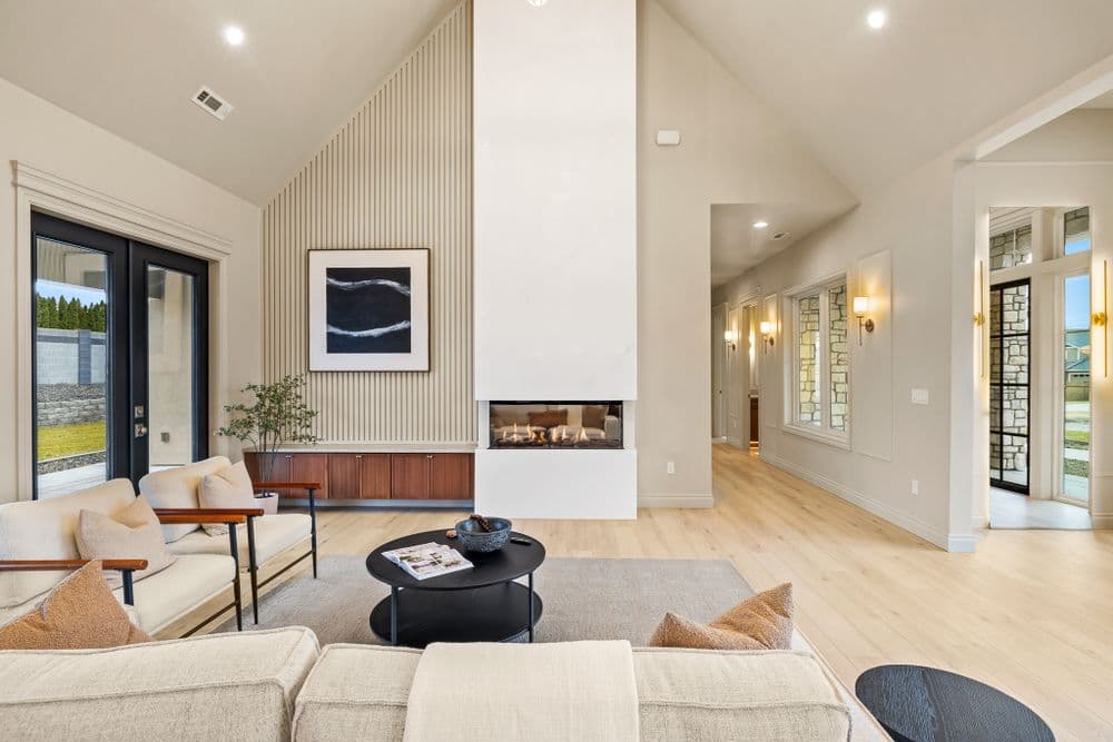 Modern living room with high ceilings, fireplace, and natural light. Stylish furniture and decor.