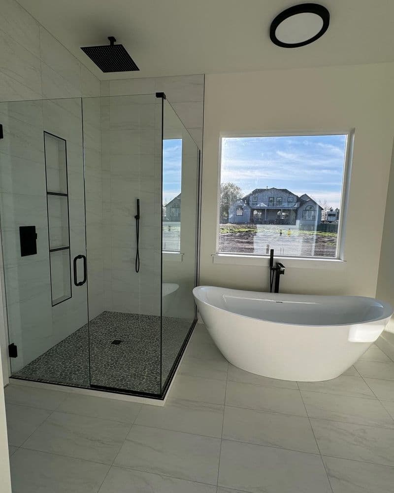 Modern bathroom featuring a walk-in shower, freestanding tub, and large window with scenic view.