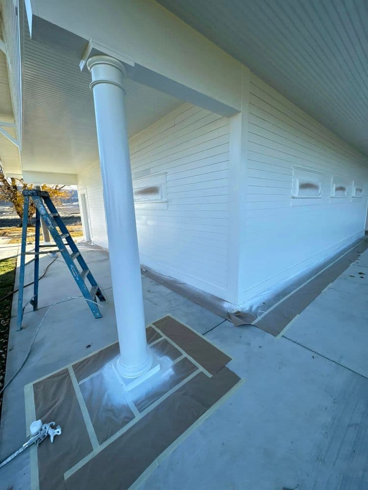 Freshly painted white house exterior with a column and ladder, showcasing meticulous renovations.