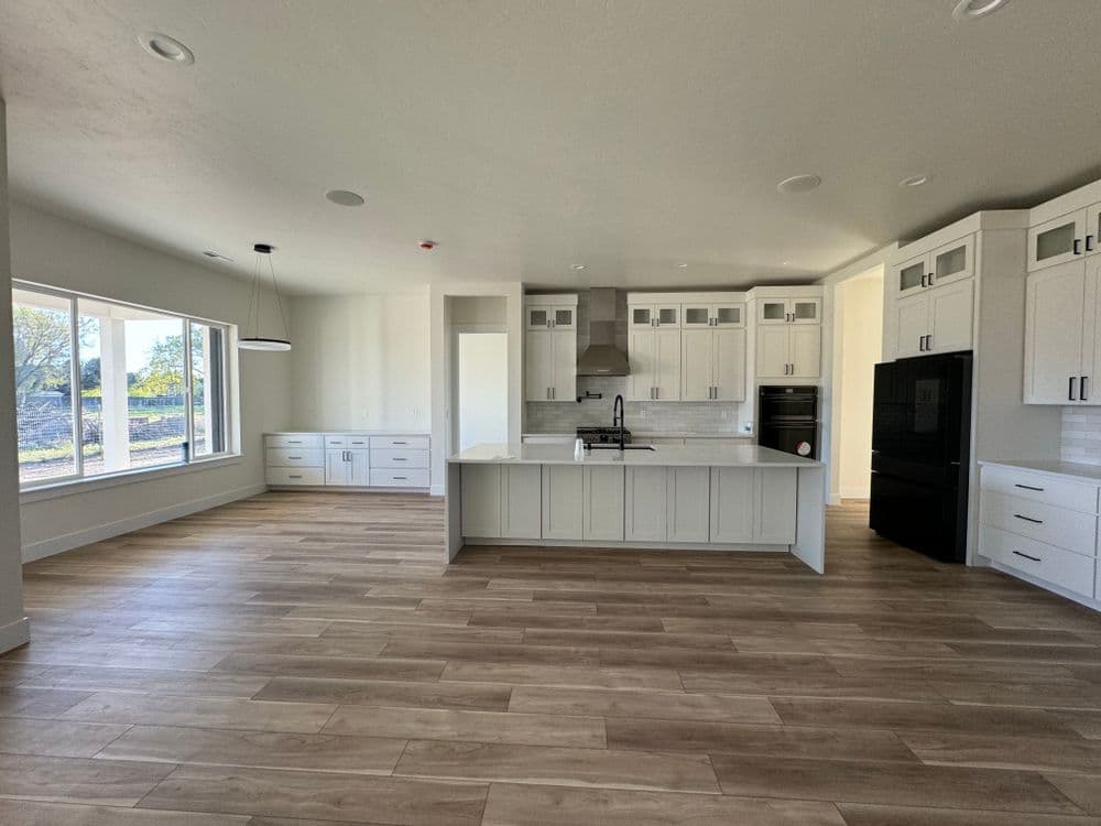 Modern kitchen interior with white cabinets, black appliances, and natural light.