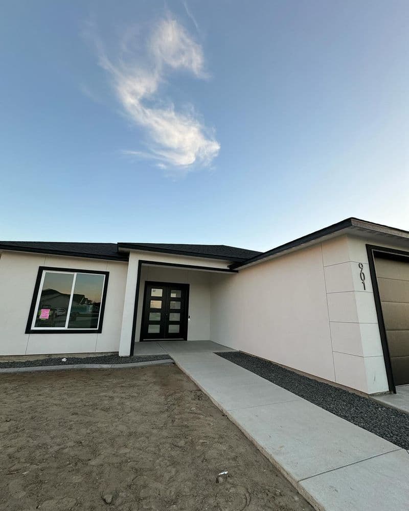 Modern single-story house with a sleek facade and clear sky background, newly built.