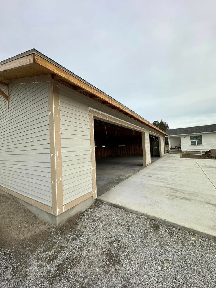 Newly constructed garage with open door, showcasing concrete flooring and exterior siding.