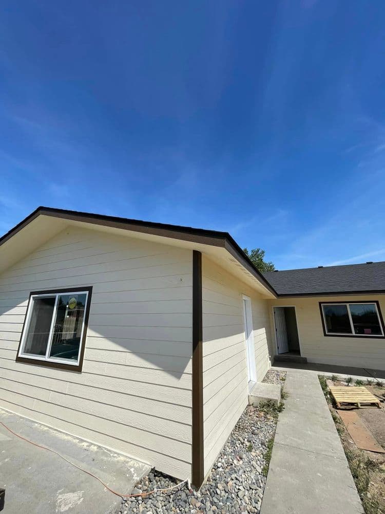 Newly renovated house exterior with a clear blue sky and walkway leading to the entrance.